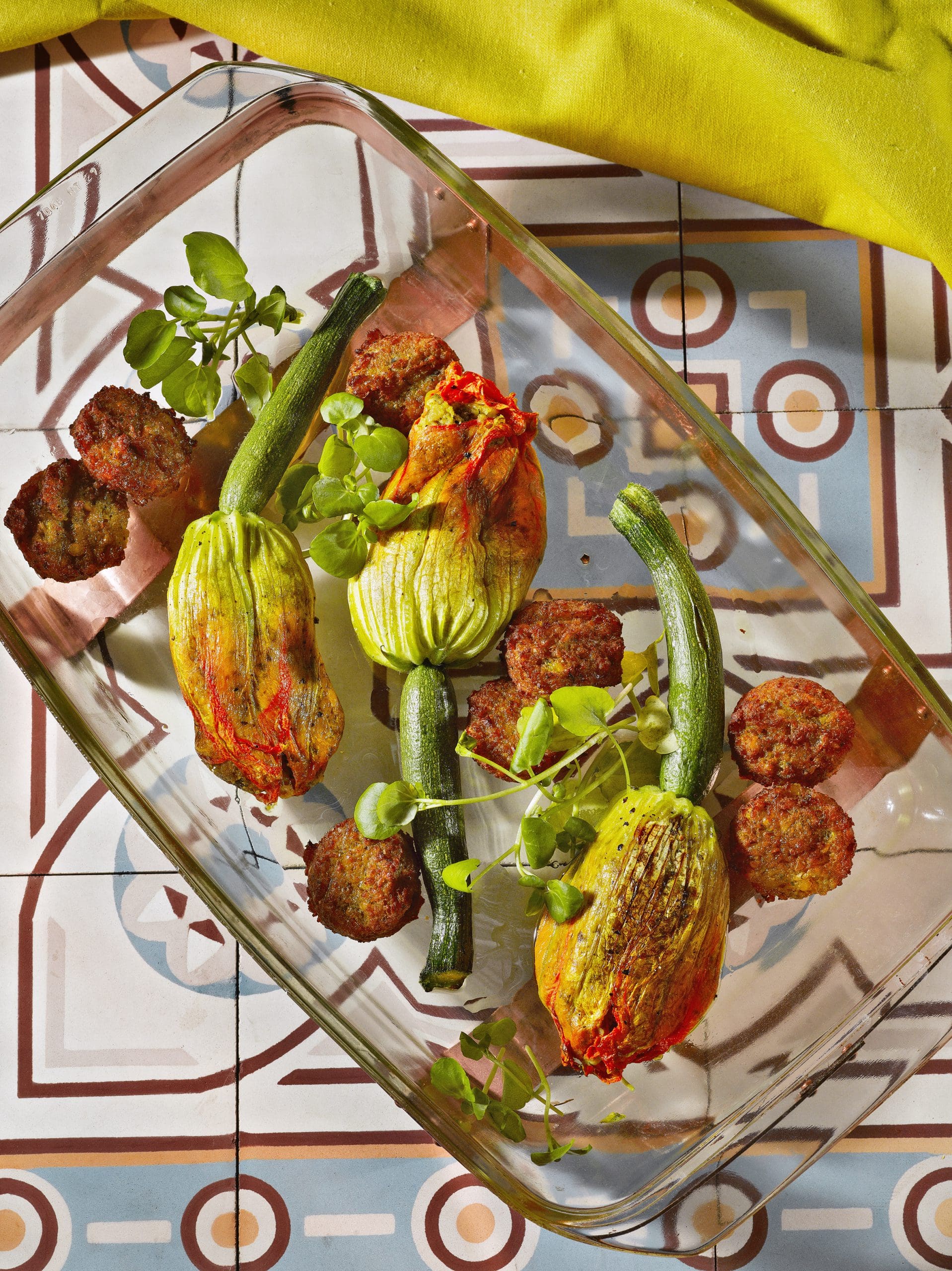 Gevulde courgettebloemen met falafel en groene kruiden in ovenschaal